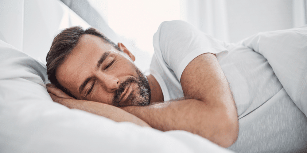 man with beard sleeping on white sheets